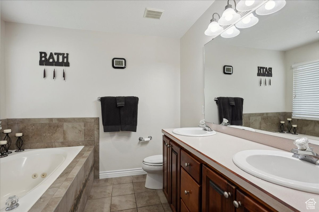 Full bath with a whirlpool tub, double vanity, tile patterned floors, and a chandelier