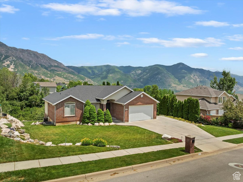 View of front of home with a mountain view, concrete driveway, an attached garage, and brick siding