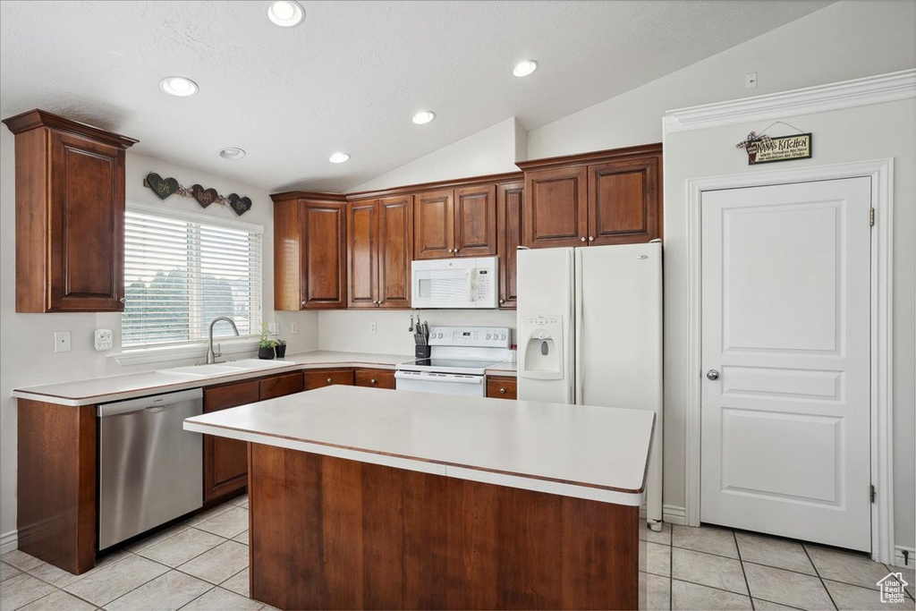 Kitchen with white appliances, lofted ceiling, light tile patterned flooring, light countertops, and a center island