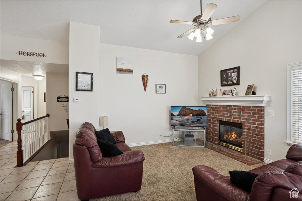 Carpeted living area featuring a ceiling fan, a fireplace, and high vaulted ceiling