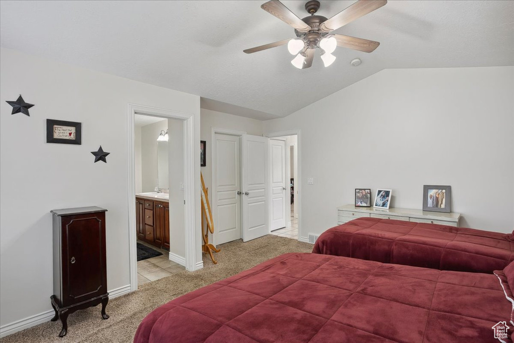 Bedroom with light colored carpet, lofted ceiling, connected bathroom, and a ceiling fan