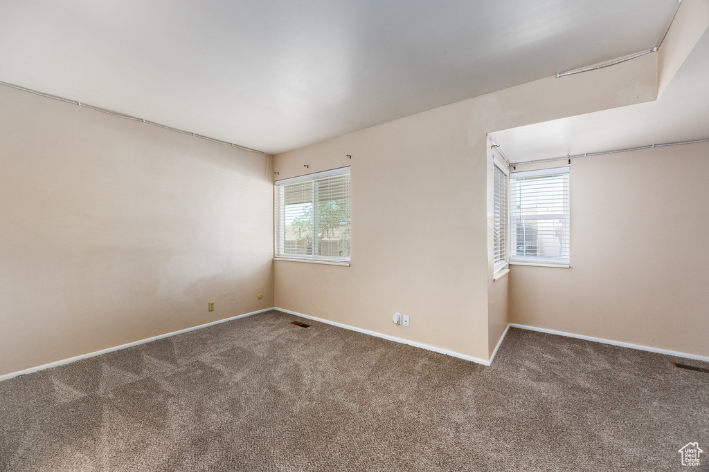 Empty room featuring healthy amount of natural light and carpet