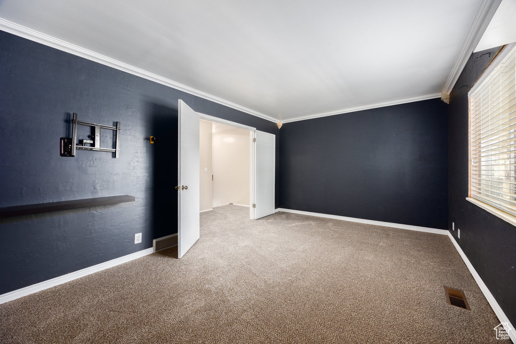 Carpeted empty room featuring ornamental molding and baseboards