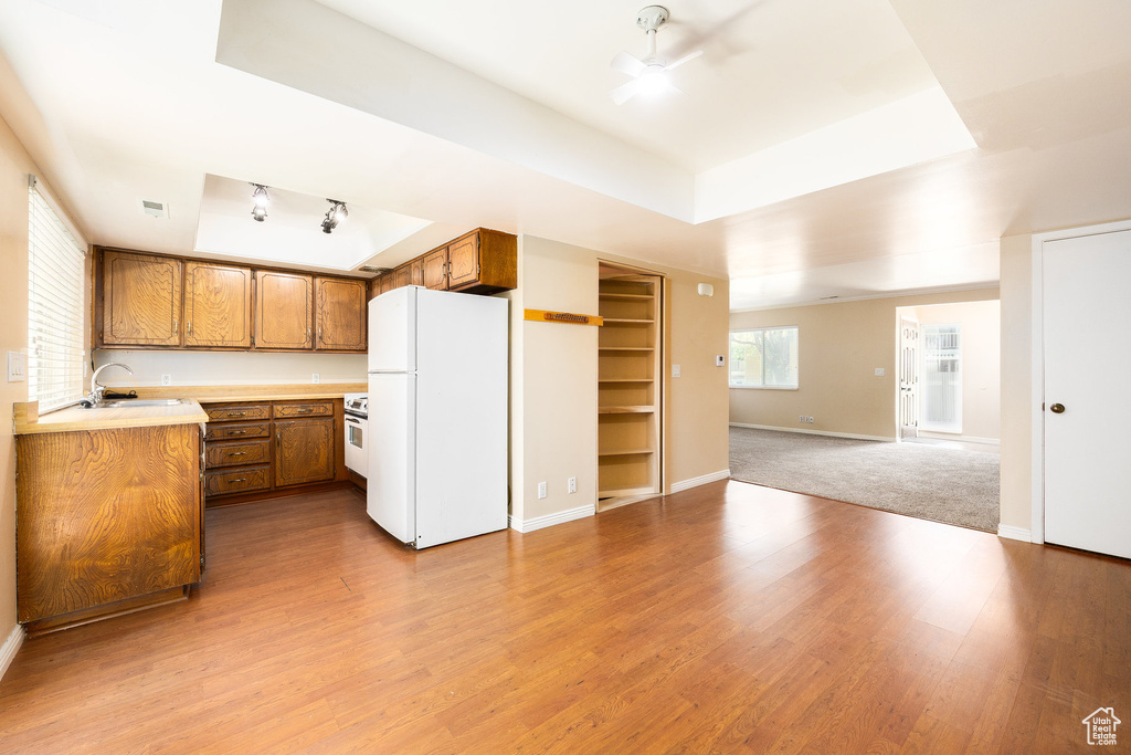 Kitchen featuring freestanding refrigerator, brown cabinets, a tray ceiling, and ceiling fan