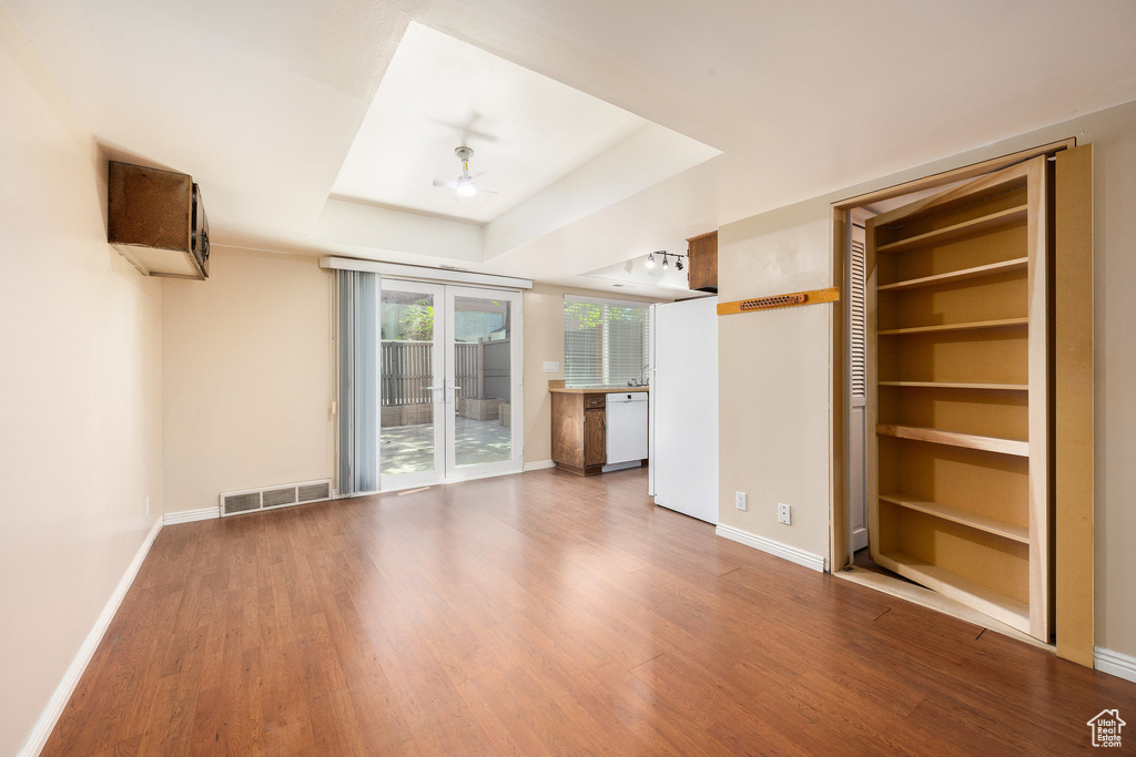 Unfurnished living room featuring wood finished floors, ceiling fan, and a raised ceiling