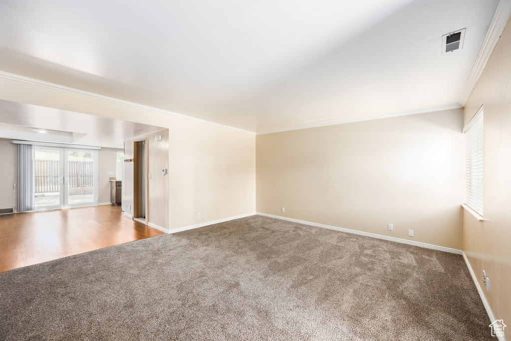 Carpeted empty room with crown molding and baseboards