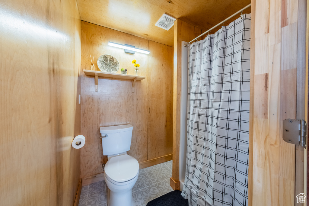 Bathroom featuring toilet and curtained shower
