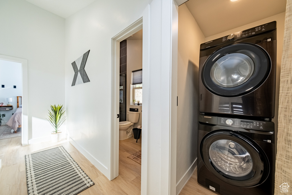 Laundry area with estacked washer and dryer and light wood-style flooring