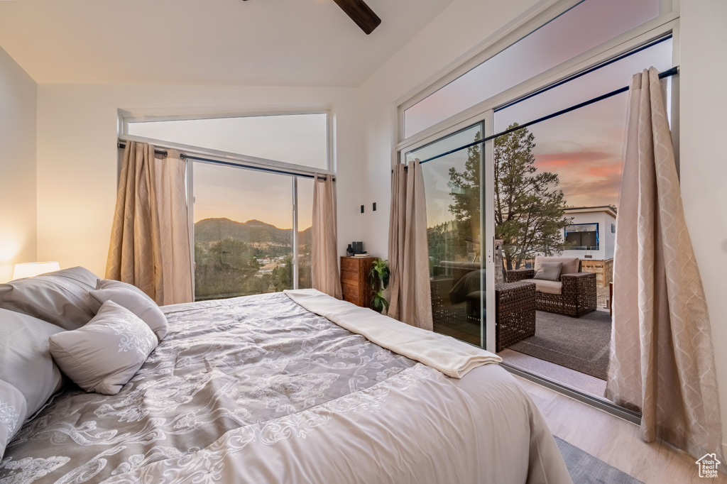 Bedroom featuring access to exterior, wood finished floors, and a ceiling fan