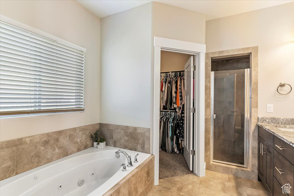 Full bathroom with a shower stall, vanity, a tub with jets, a walk in closet, and tile patterned floors