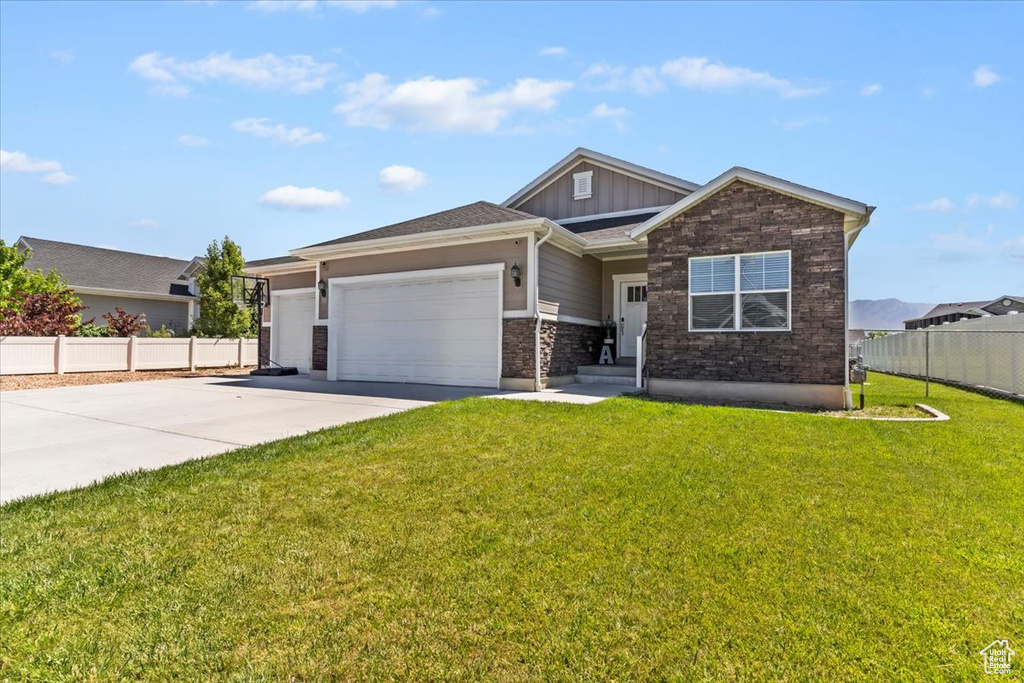 View of front of property featuring board and batten siding, an attached garage, driveway, and stone siding