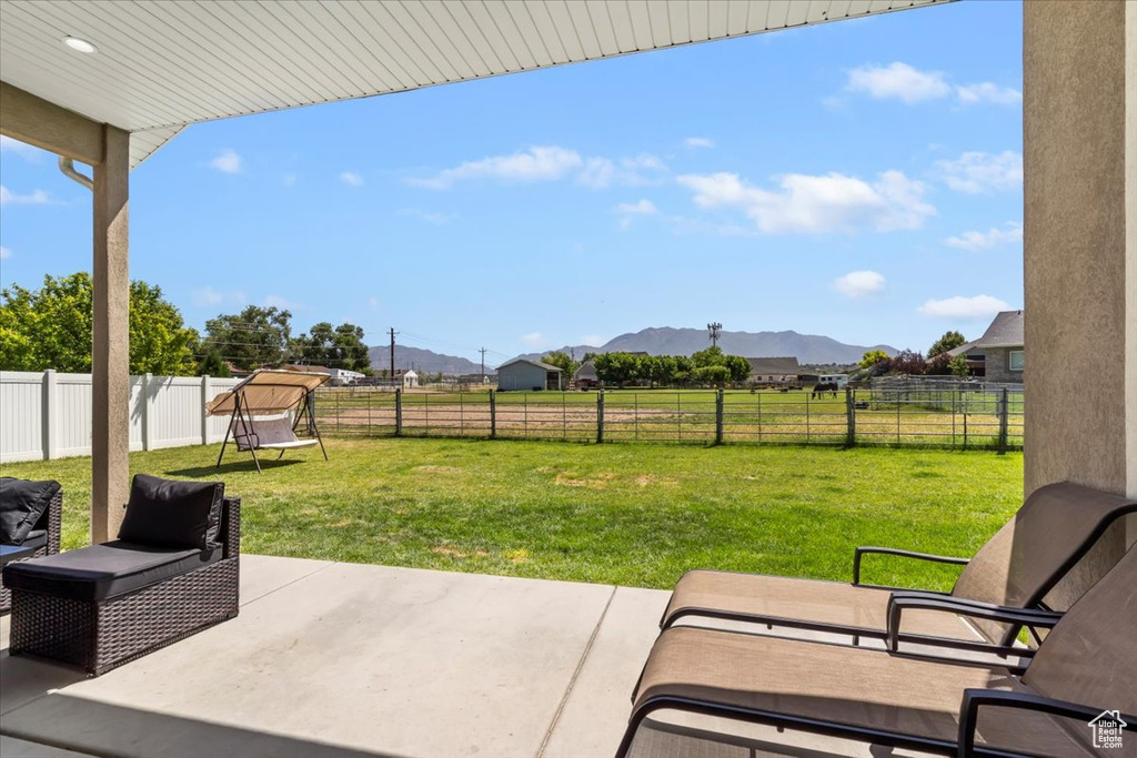 Fenced backyard featuring a mountain view, a patio, and a view of countryside