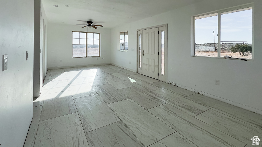 Foyer entrance featuring a ceiling fan and baseboards