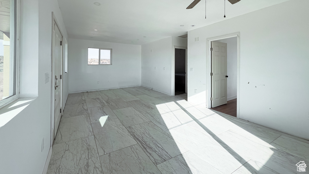 Unfurnished room featuring a ceiling fan and light marble finish floors