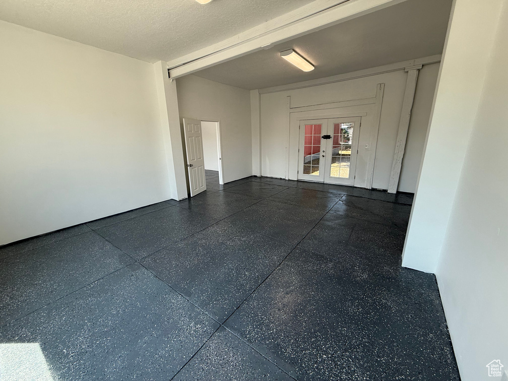 Empty room featuring french doors and speckle patterned floor
