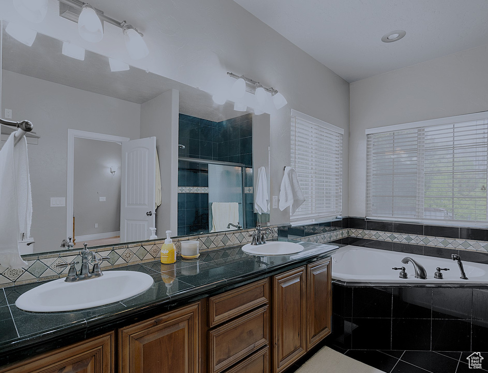 Full bathroom featuring a stall shower, double vanity, a bath, and tile patterned floors