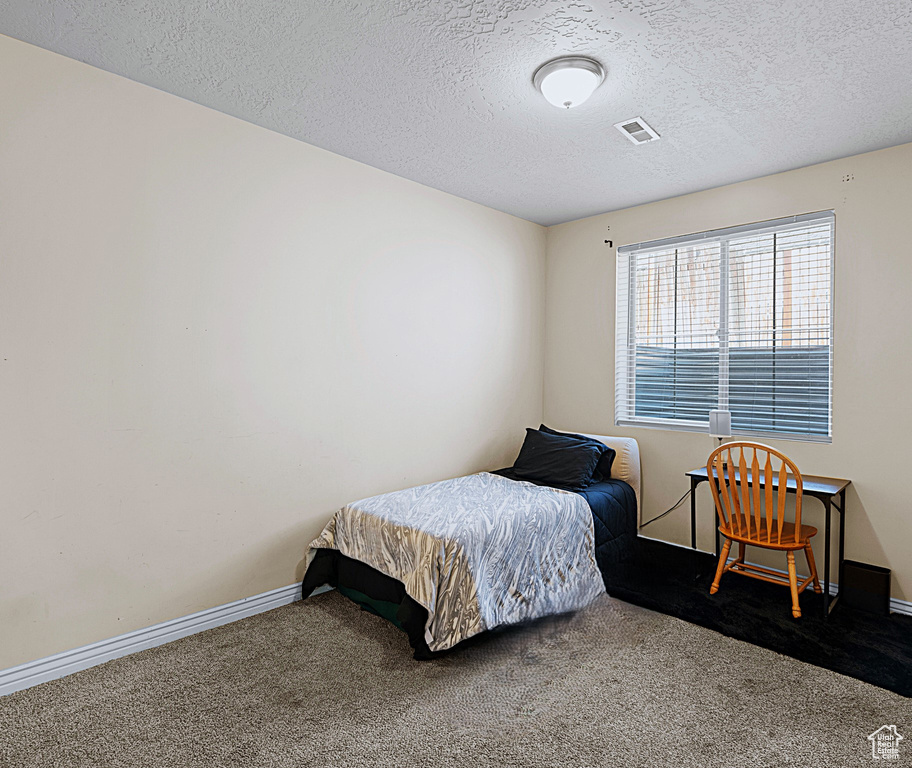 Carpeted bedroom with a textured ceiling and baseboards