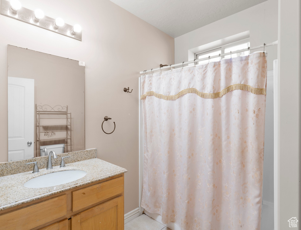 Full bathroom with vanity, a shower with shower curtain, and tile patterned flooring