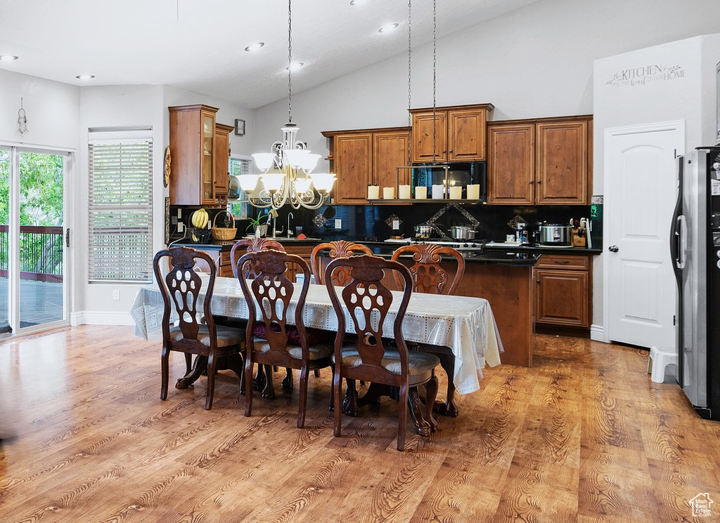 Kitchen featuring dark countertops, brown cabinets, tasteful backsplash, a chandelier, and light wood finished floors