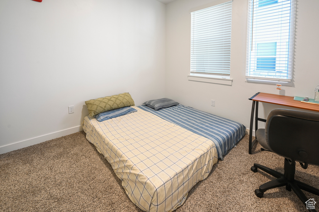 Bedroom featuring light carpet and a desk