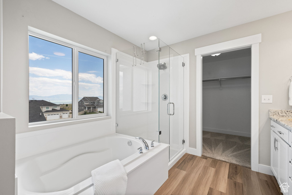 Bathroom featuring a shower stall, a bath, wood finished floors, and vanity