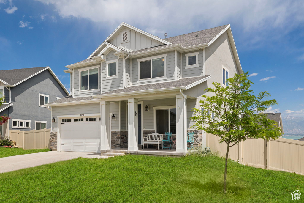 Craftsman inspired home featuring a porch, a garage, driveway, board and batten siding, and roof with shingles