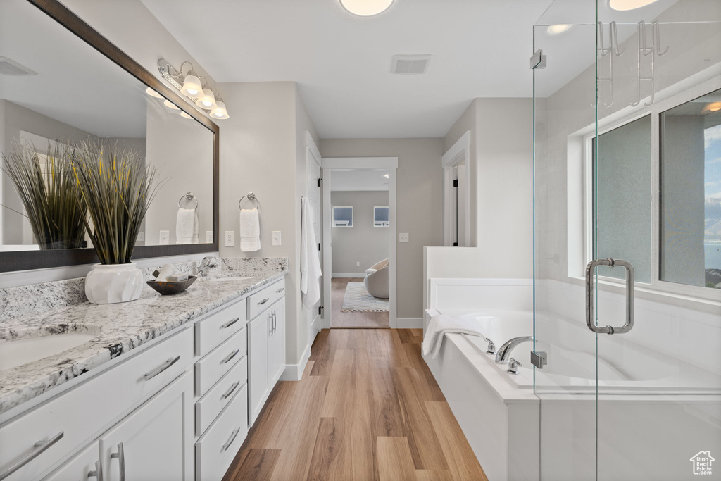 Full bath featuring double vanity, a bath, wood finished floors, and a shower stall
