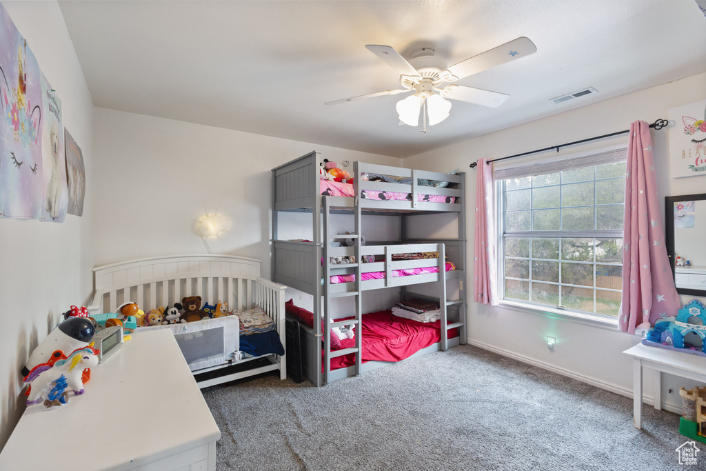Carpeted bedroom featuring ceiling fan and baseboards