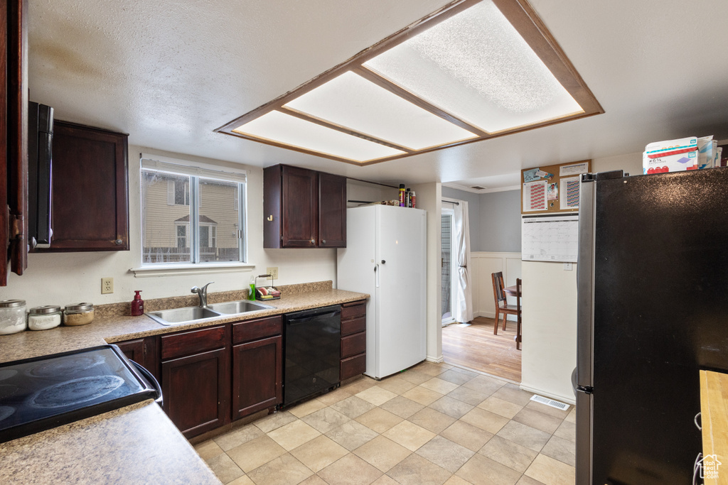 Kitchen with freestanding refrigerator, dishwasher, dark brown cabinets, and light countertops