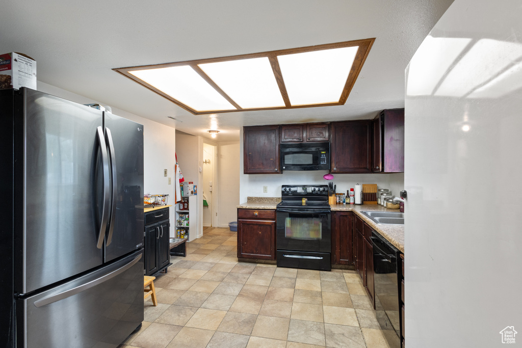 Kitchen with black appliances, light countertops, and dark brown cabinetry
