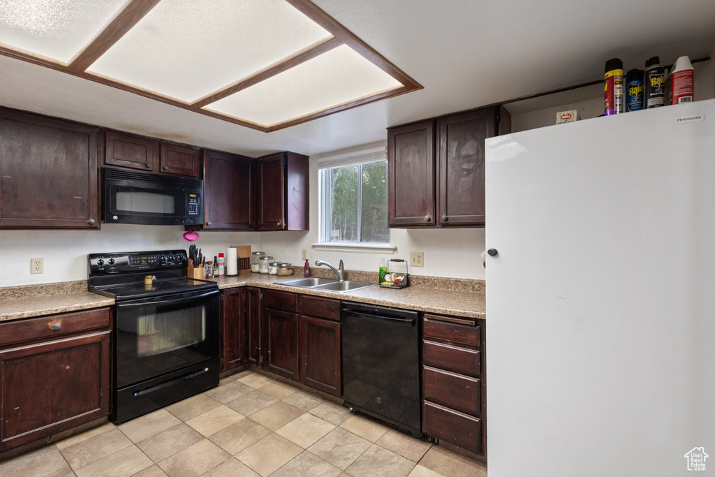 Kitchen featuring black appliances, light countertops, and dark brown cabinetry
