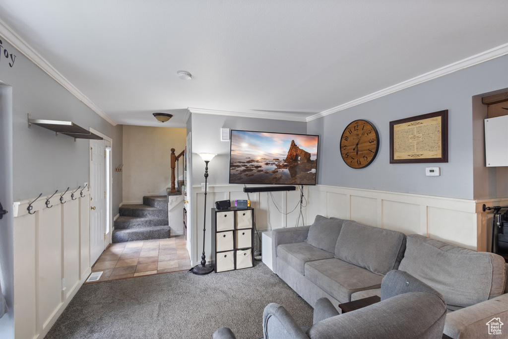 Living area with crown molding, carpet, stairs, a wainscoted wall, and a decorative wall
