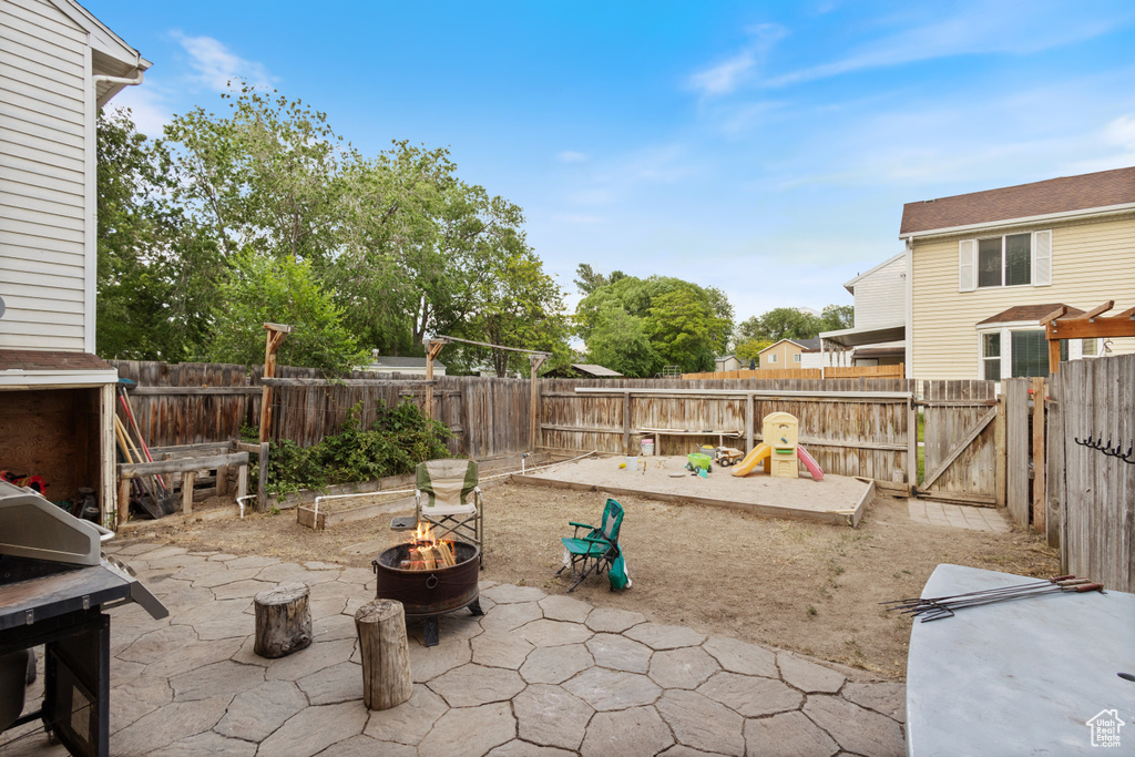 Fenced backyard featuring a fire pit, a patio area, and a grill
