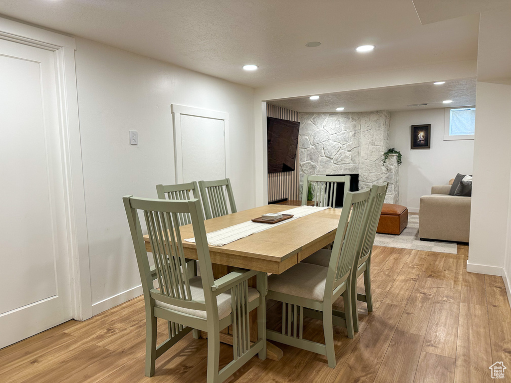 Dining area featuring light wood-style floors, a stone fireplace, and recessed lighting