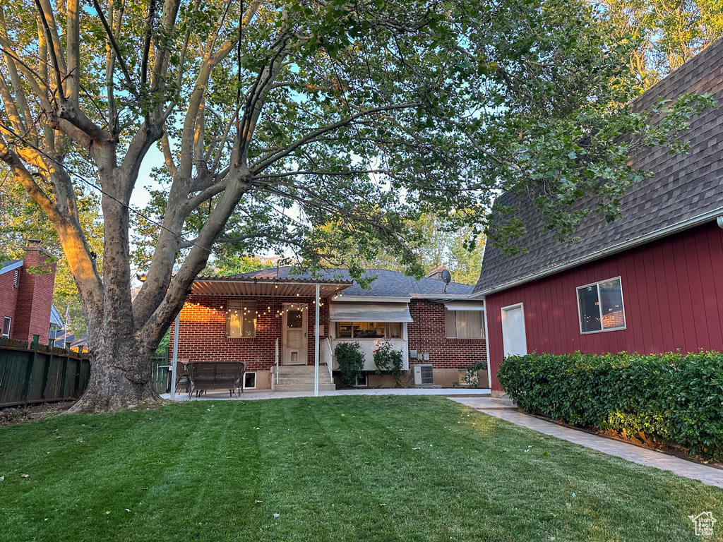 Back of house with a pergola, roof with shingles, a patio area, and brick siding