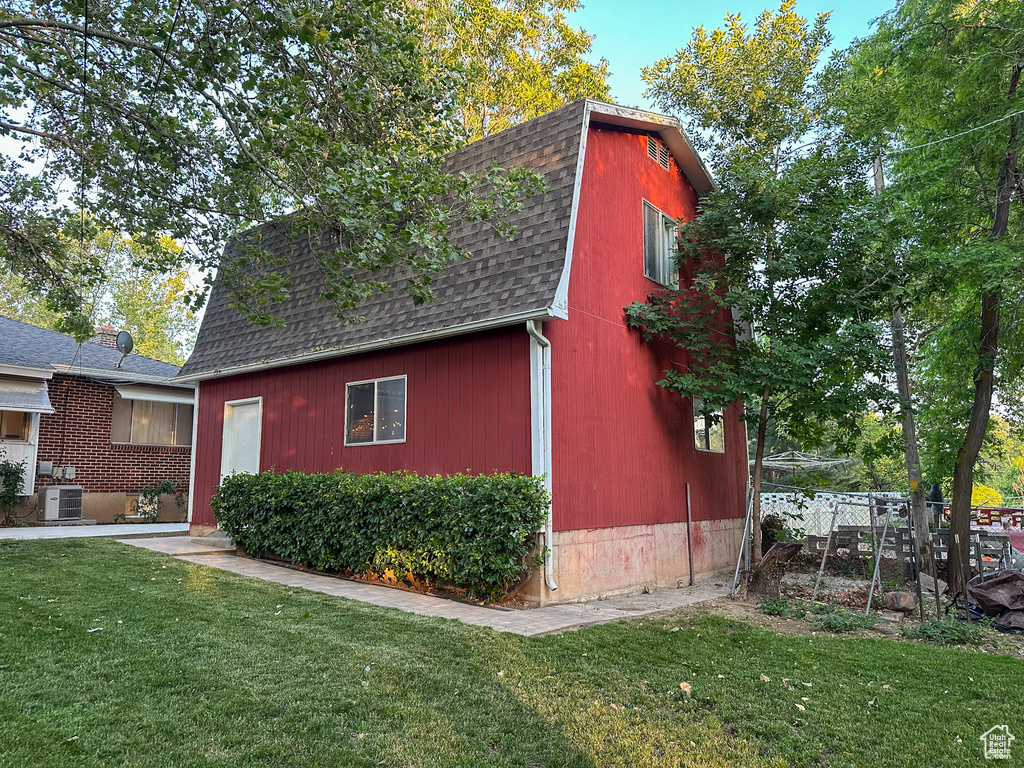 View of property exterior featuring roof with shingles, a yard, and a gambrel roof