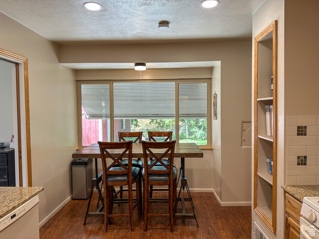 Dining room featuring dark wood finished floors, recessed lighting, and a textured ceiling