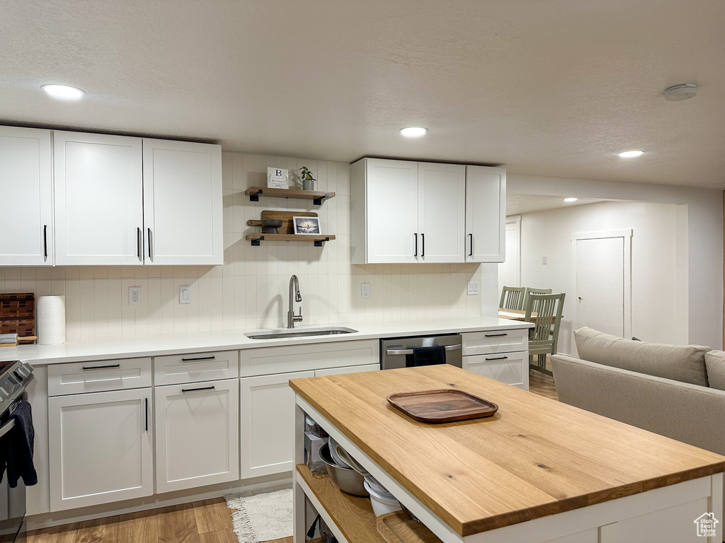 Kitchen featuring butcher block countertops, stainless steel appliances, open shelves, white cabinetry, and recessed lighting