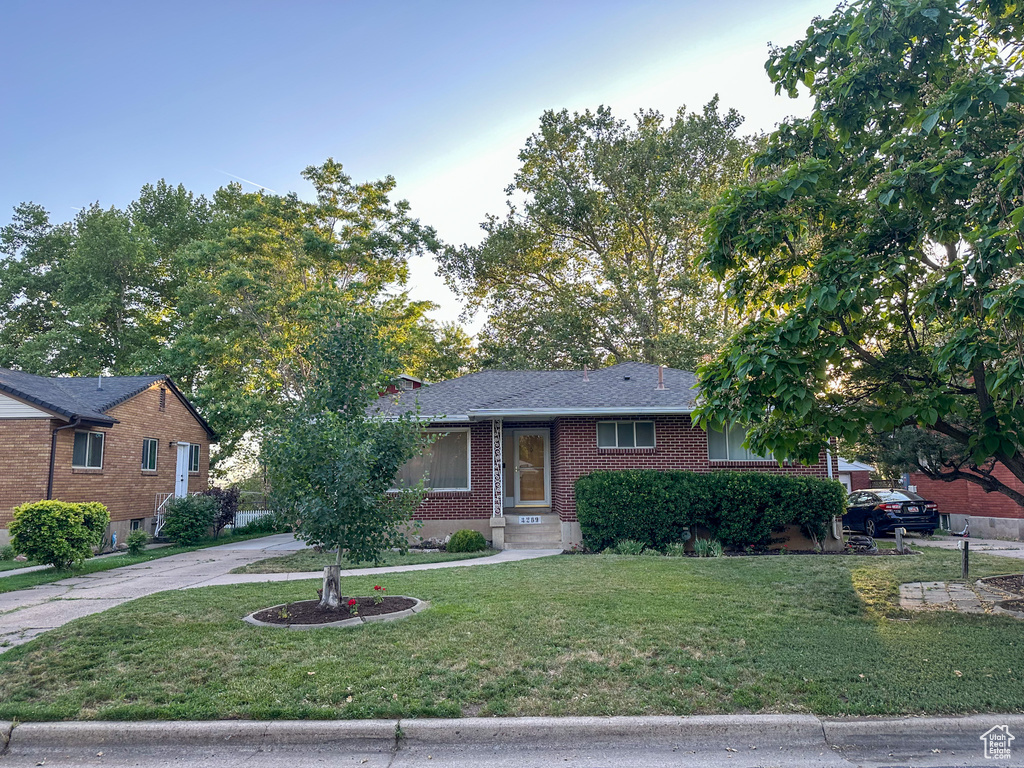 Ranch-style house featuring a front lawn, brick siding, and concrete driveway