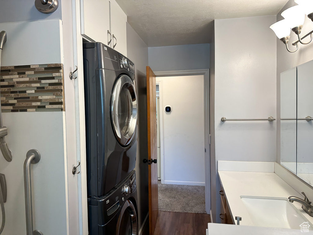 Washroom featuring stacked washer and clothes dryer, dark wood finished floors, and a textured ceiling