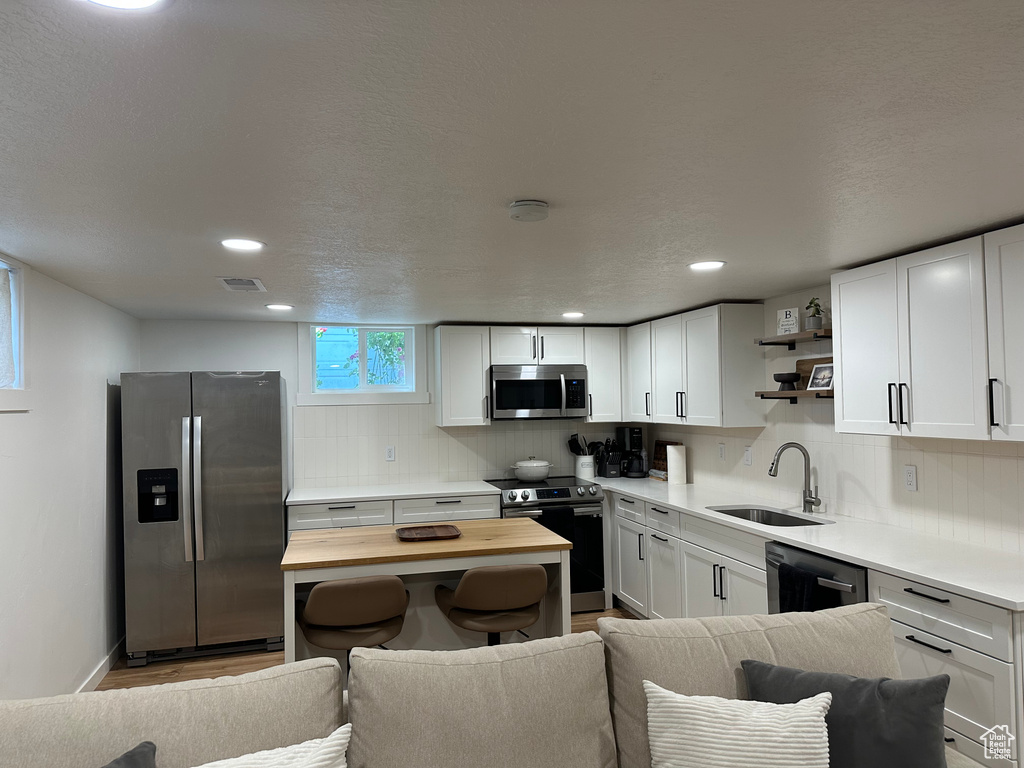 Kitchen with stainless steel appliances, wood counters, open shelves, tasteful backsplash, and white cabinets