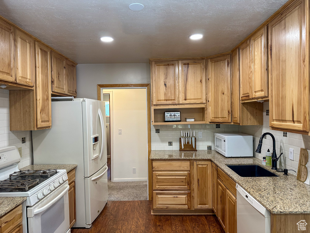 Kitchen featuring white appliances, decorative backsplash, open shelves, dark wood-type flooring, and light stone counters
