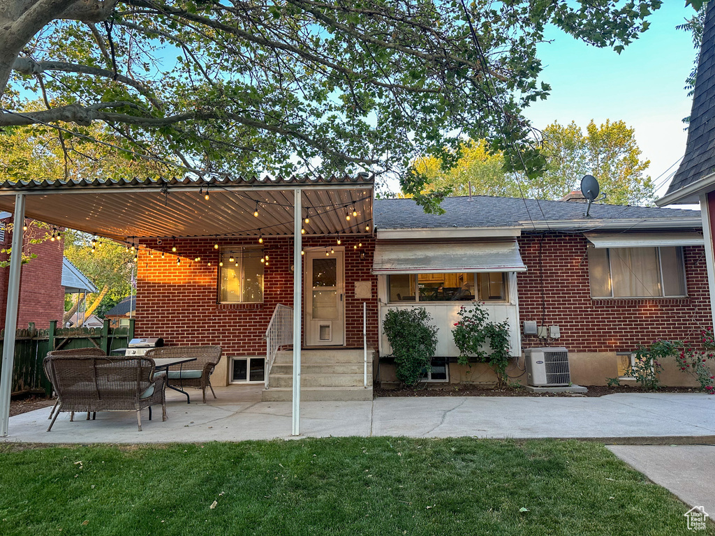 Rear view of house featuring brick siding, a patio area, and a shingled roof