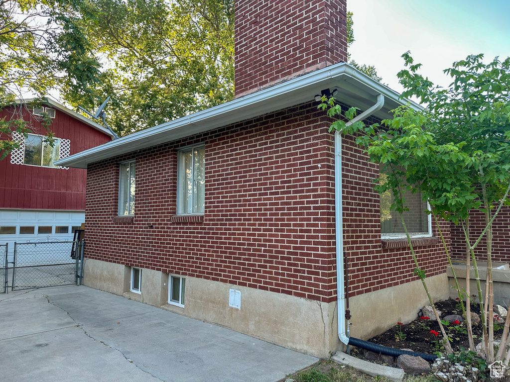View of home\\\\\\\'s exterior featuring a garage, brick siding, and a chimney