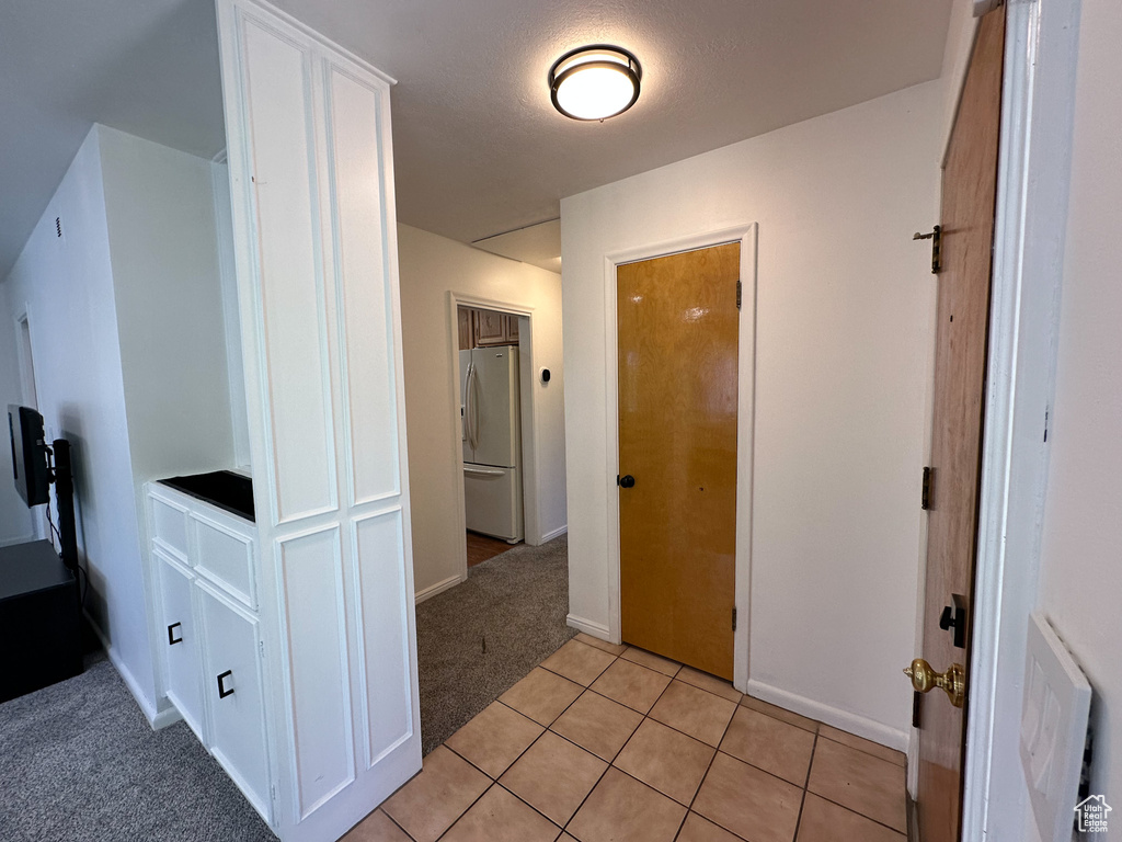Hall featuring light colored carpet and light tile patterned floors