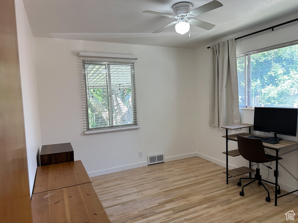 Office with healthy amount of natural light, wood finished floors, and a ceiling fan