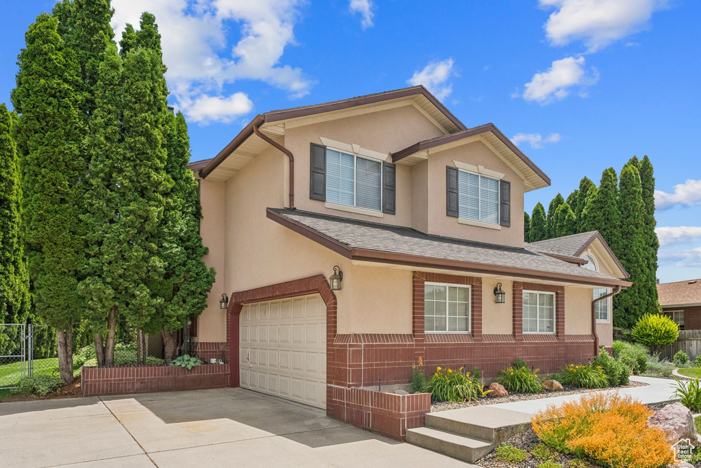 View of front facade featuring a garage, stucco siding, and driveway