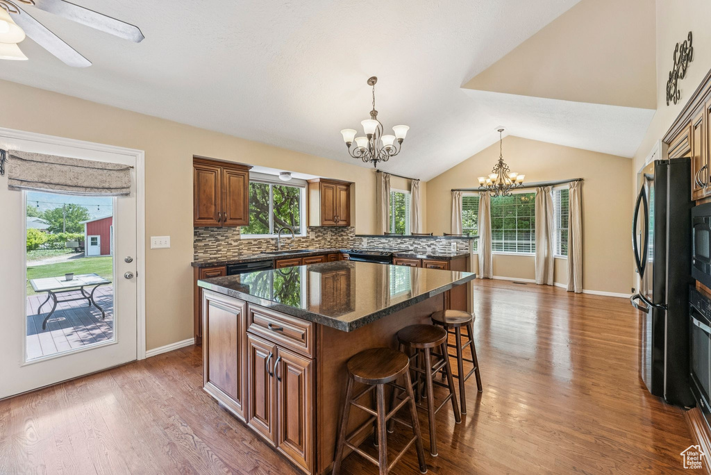 Kitchen featuring a chandelier, a kitchen breakfast bar, a kitchen island, black appliances, and tasteful backsplash