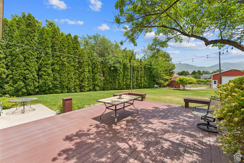 Deck featuring a mountain view, a lawn, and an outbuilding