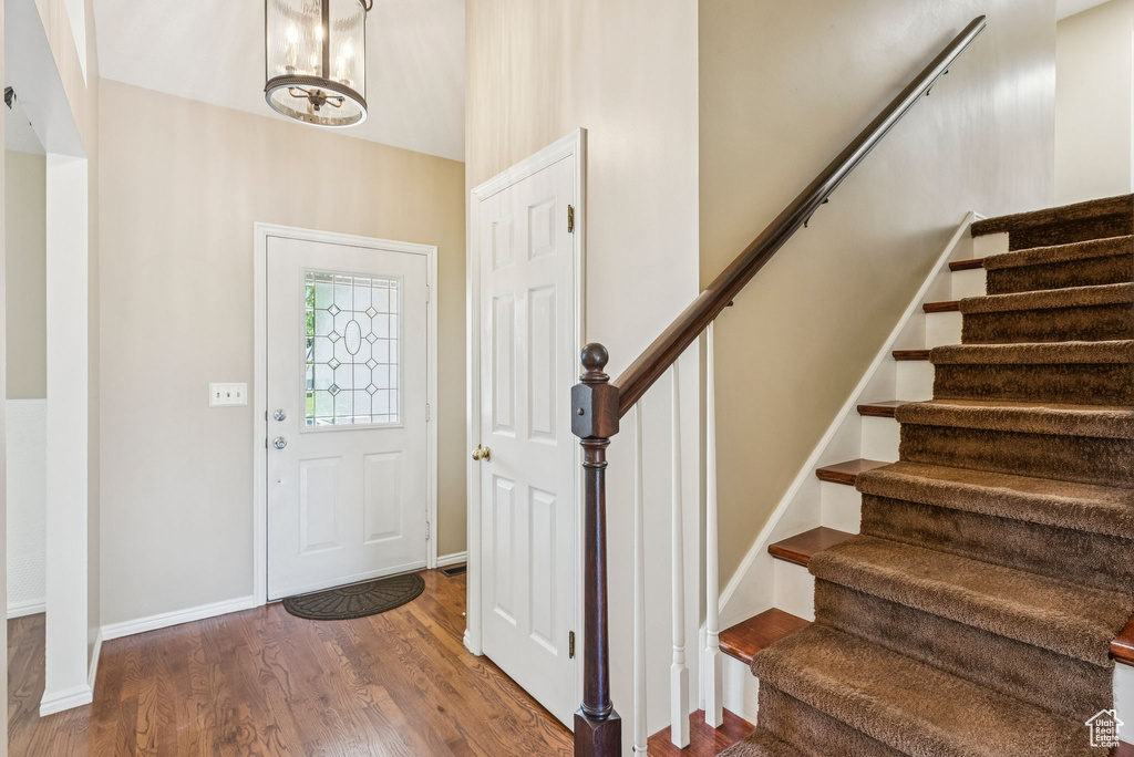 Foyer entrance with stairs, wood finished floors, and a chandelier